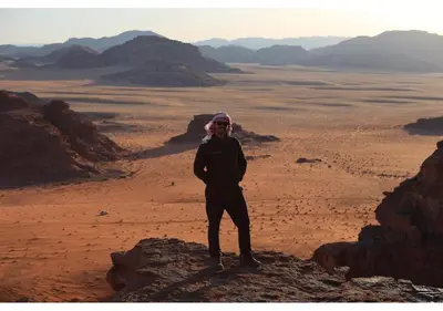 a man standing on a rock in the desert at Wadi rum stay & tours in Wadi Rum