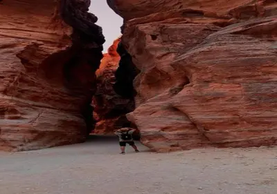 a person standing in front of a rock wall at Wadi rum stay & tours in Wadi Rum
