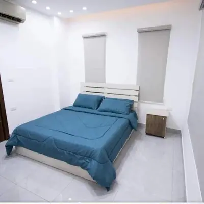 a bedroom with a blue bed in a white room at Gerasa Breeze resort in Rujm al Miḑmār