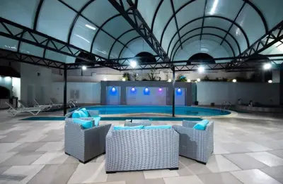 a swimming pool with chairs in a large building at Gerasa Breeze resort in Rujm al Miḑmār