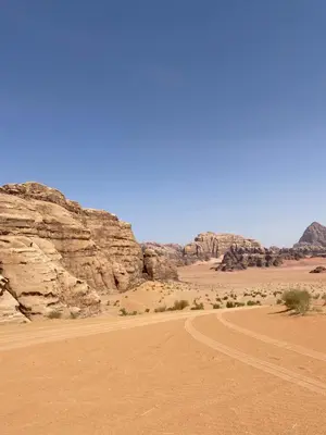 a dirt road in the desert with mountains in the background at desert Hawk in Wadi Rum