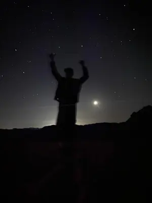 a man standing on a hill under the stars at desert Hawk in Wadi Rum