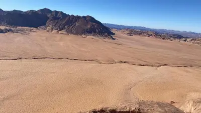 an empty desert with a mountain in the background at desert Hawk in Wadi Rum