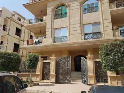 a large building with a gate and cars parked in front at Samira House in Amman