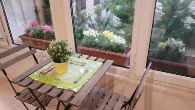 a table and chairs in a room with flowers on the windows at Two Bedroom Shmeisani Apartment in Amman