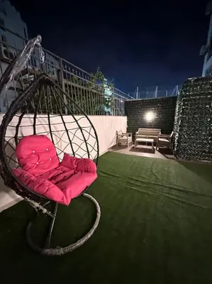 a red chair sitting on top of a yard at Stylish Luxe Apartment F/R 0001 in Amman