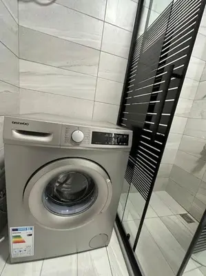 a washing machine in a bathroom with a wall at Stylish Luxe Apartment F/R 0001 in Amman