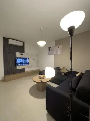 a living room with a black couch and a table at Stylish Luxe Apartment F/R 0001 in Amman