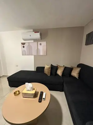 a living room with a black couch and a table at Stylish Luxe Apartment F/R 0005 in Amman