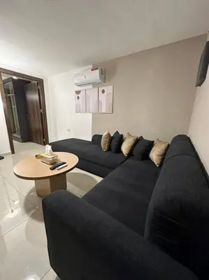a living room with a black couch and a table at Stylish Luxe Apartment F/R 0005 in Amman