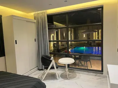 a bedroom with a bed and a table and a pool at Tixos Farm in Irbid