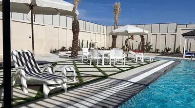 a pool with chairs and umbrellas and a table and chairsitures at Tixos Farm in Irbid