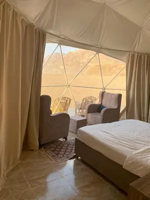 a bedroom with a bed and chairs in a tent at Wadi Rum Sarab Camp in Disah