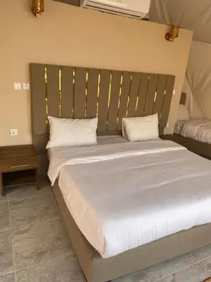 a large bed with a wooden headboard in a bedroom at Wadi Rum Sarab Camp in Disah