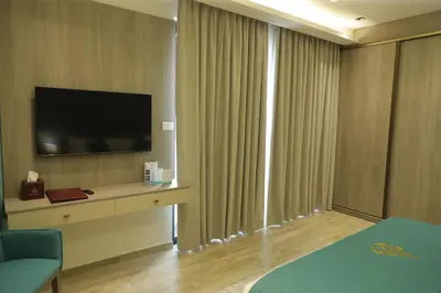 a hotel room with a flat screen tv and curtains at Soho Midtown in Ash Shumaysānī