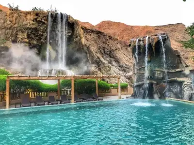 a waterfall and pool at a resort with chairs and a waterfall at Laura's Stylish Villa in Madaba