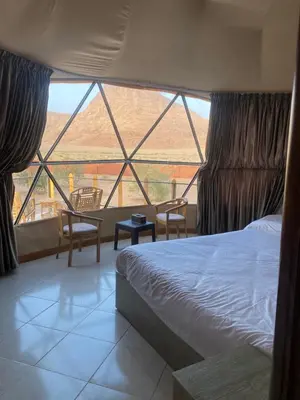 a bedroom with a bed and a large window at Omar Camp Wadi Rum in Disah