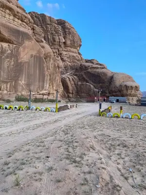 a dirt road in front of a rock wall at Camp safaa rum in Wadi Rum