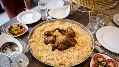 a table with a plate of food with chicken on rice at look house in Amman