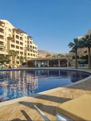 a large swimming pool with palm trees and buildings at Samarah Resort D32 in Sowayma
