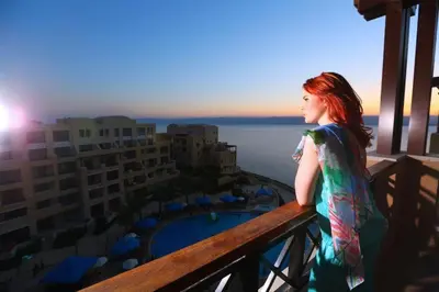 a woman standing on a balcony looking out at the ocean at Samarah Resort D32 in Sowayma