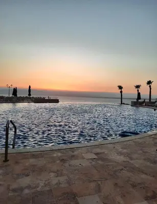 a swimming pool with a sunset in the background at Samarah Resort D32 in Sowayma