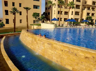 two people in a swimming pool at a hotel at Samarah Resort D32 in Sowayma