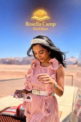 a woman in a pink dress looking at her cell phone at Rosella Camp Wadi Rum in Wadi Rum