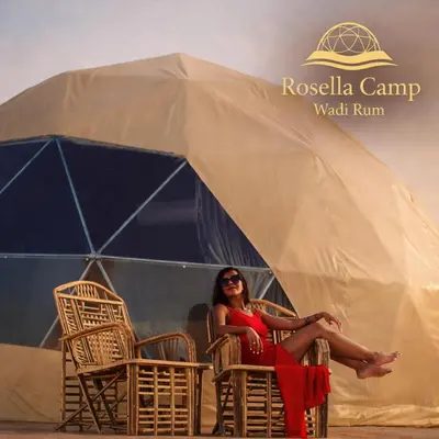 a woman in a red dress sitting inront of a tent at Rosella Camp Wadi Rum in Wadi Rum