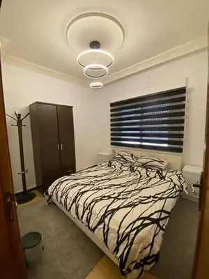 a bedroom with a bed with a black and white comforter at Nerman home in ‘Awjān ash Shamālī
