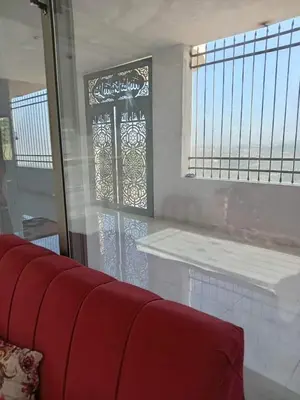 a living room with a red couch and a window at Nerman home in ‘Awjān ash Shamālī