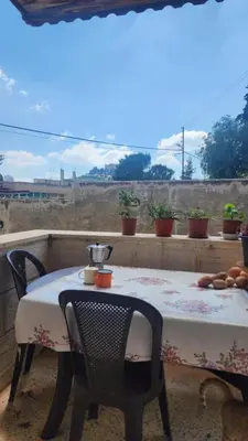a table and chairs on a balcony with a view of a field at Blackbird Sanctuary homestay & Art Cafe in Ajloun