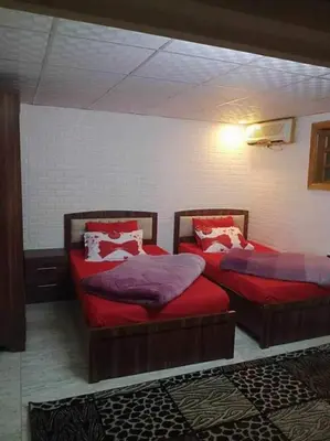 two beds with red sheets in a room at Araregj home in Amman