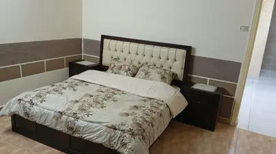 a bedroom with a large bed with a large headboard at شقة الياسمين العائلية الفاخرة in Amman