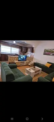 a living room with green couches and a flat screen tv at Maan 12 in Ma‘ān