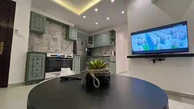 a kitchen with a table and a tv on a wall at Casa De Centre 2 in Amman