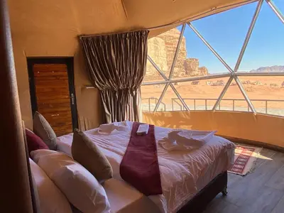 a bedroom with a bed and a large window at Wadi Rum, sands of Mars in Wadi Rum
