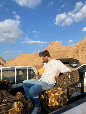a man sitting on the back of a truck in the desert at Wadi Rum, sands of Mars in Wadi Rum