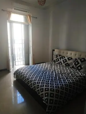 a bedroom with a bed and a large window at GOJORDAN INN in Irbid