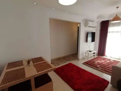 a living room with a table and a red rug at lomez House in Amman