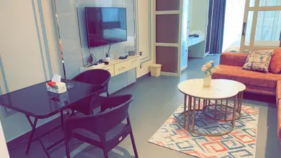 a living room with a table and a tv at Amman Damac one bedroom boulevard Abdali استديو في داماك عمان الاردن in Amman