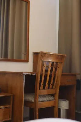 a wooden chair sitting next to a desk with a mirror at Hotel Rayshan in Amman