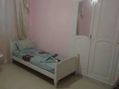 a small bed in a white room with a door at 360 INNn in Irbid