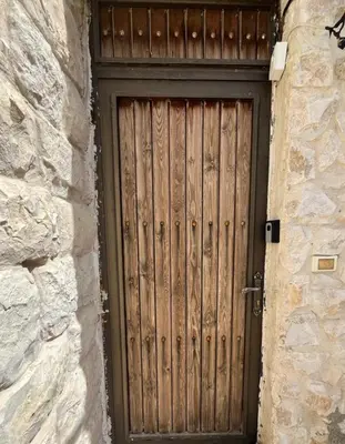 a wooden door in a stone building with a stone wall at Al Karak House sharing Apt in Kerak
