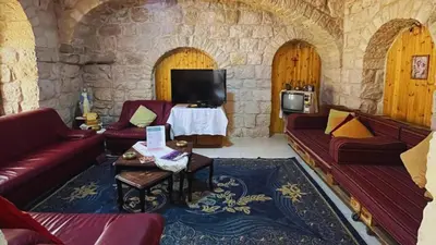 a living room with red couches and a tv at Al Karak House sharing Apt in Kerak
