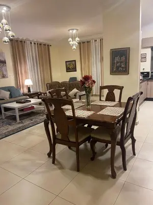 a living room with a wooden table and chairs at Sunset Balcony Retreat - Spacious and Comfortable 2 Bedrooms 2 Bathrooms in Amman