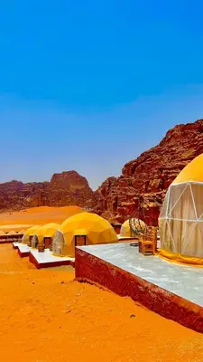 a row of tents in the desert with mountains at Wadi Rum Luxure desert Camp in Wadi Rum