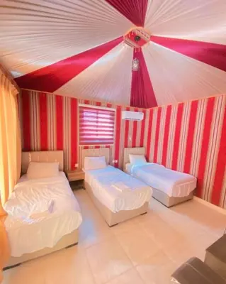 a room with two beds and a red and white ceiling at Wadi Rum Luxure desert Camp in Wadi Rum