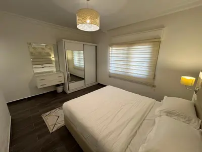 a bedroom with a bed and a dresser and a mirror at COZY apt For long &short Stay in Amman
