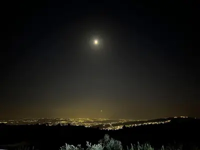 a moon in the sky over a city at night at شاليه جبال سوف in Jerash